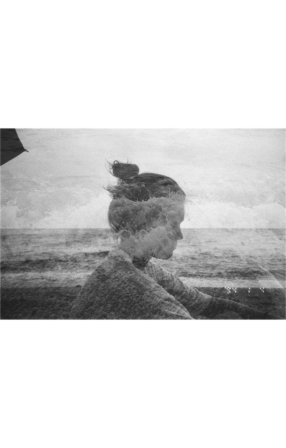 Fotografía en blanco y negro de un retrato doble con superposición del perfil de una mujer y una escena marina.