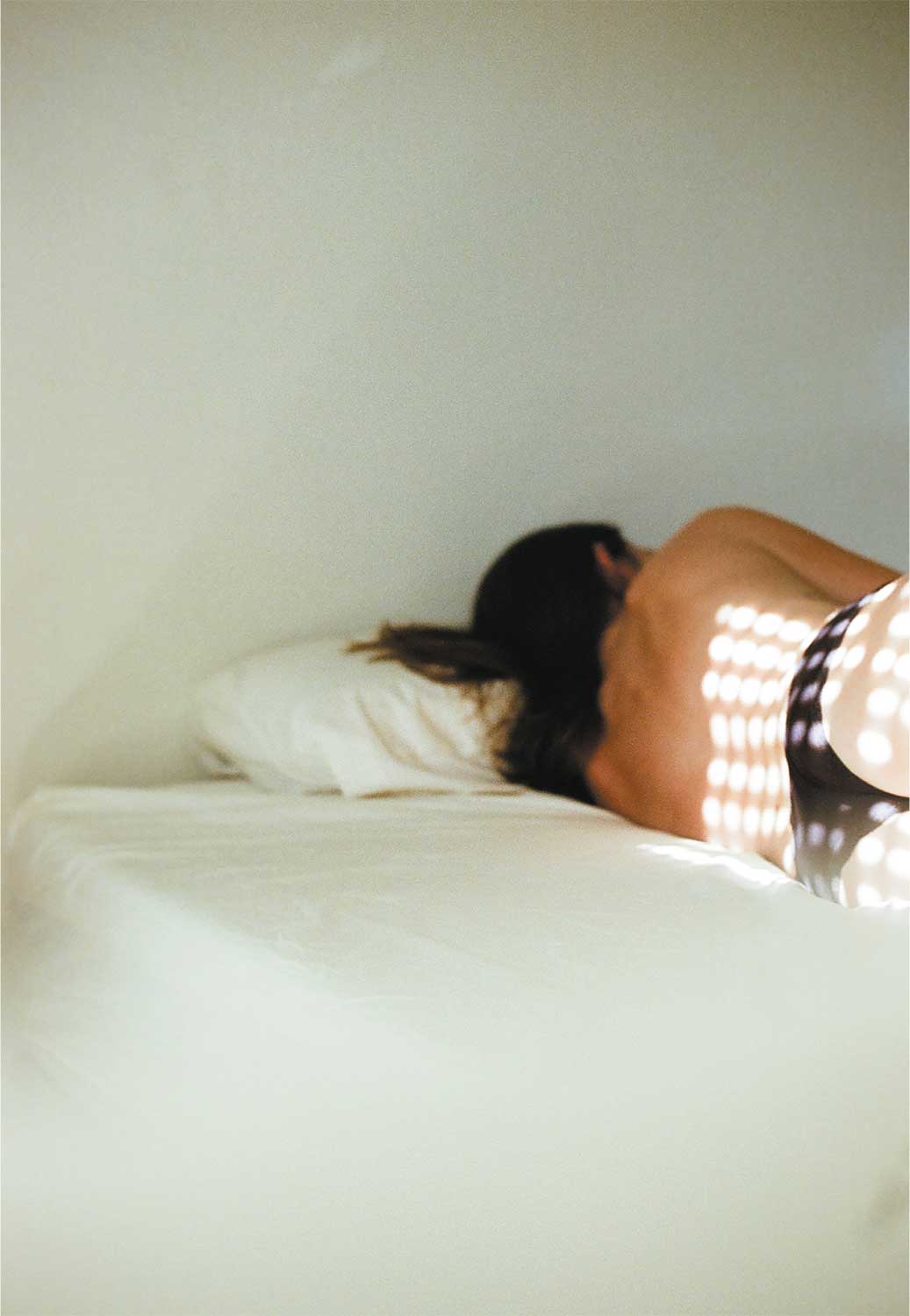 Fotografía de una persona tumbada boca abajo sobre una cama, con la cabeza apoyada en una almohada.